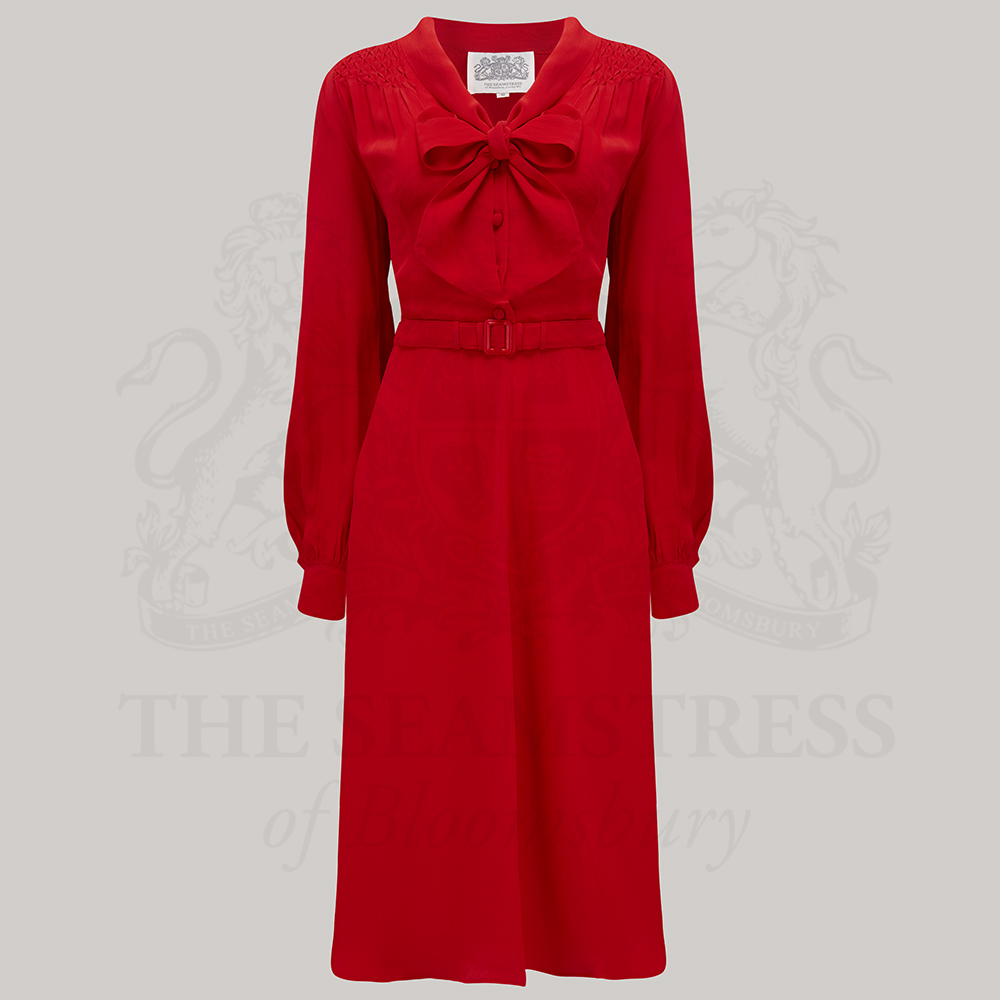 A vintage-inspired red dress with a pussy-bow neckline, long sleeves, and smock stitching on the shoulders. 